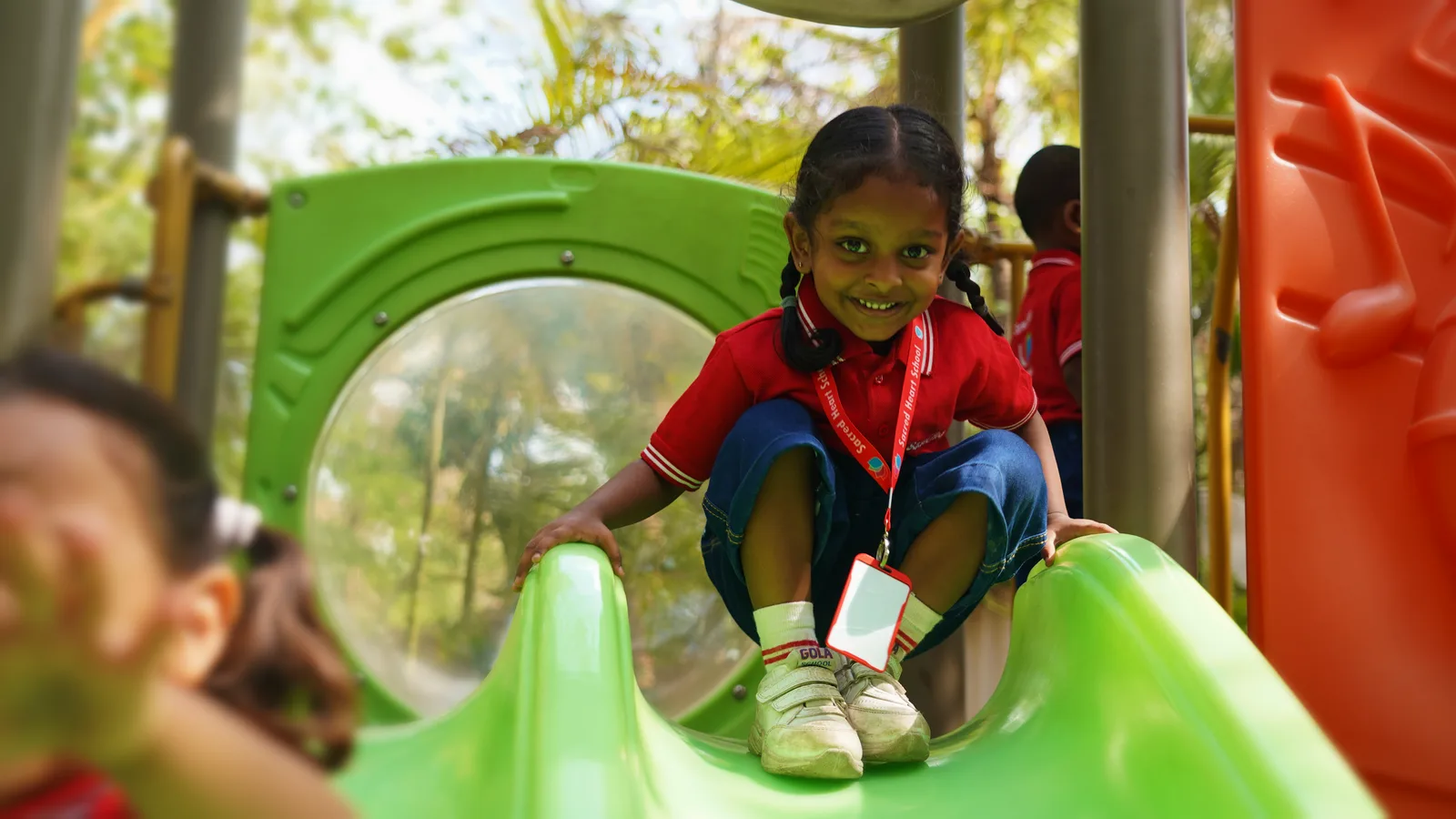 A young student playing on the playground slide