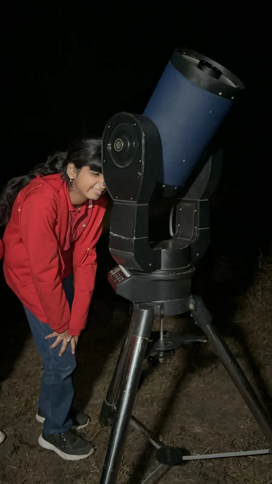 A student using a telescope at night