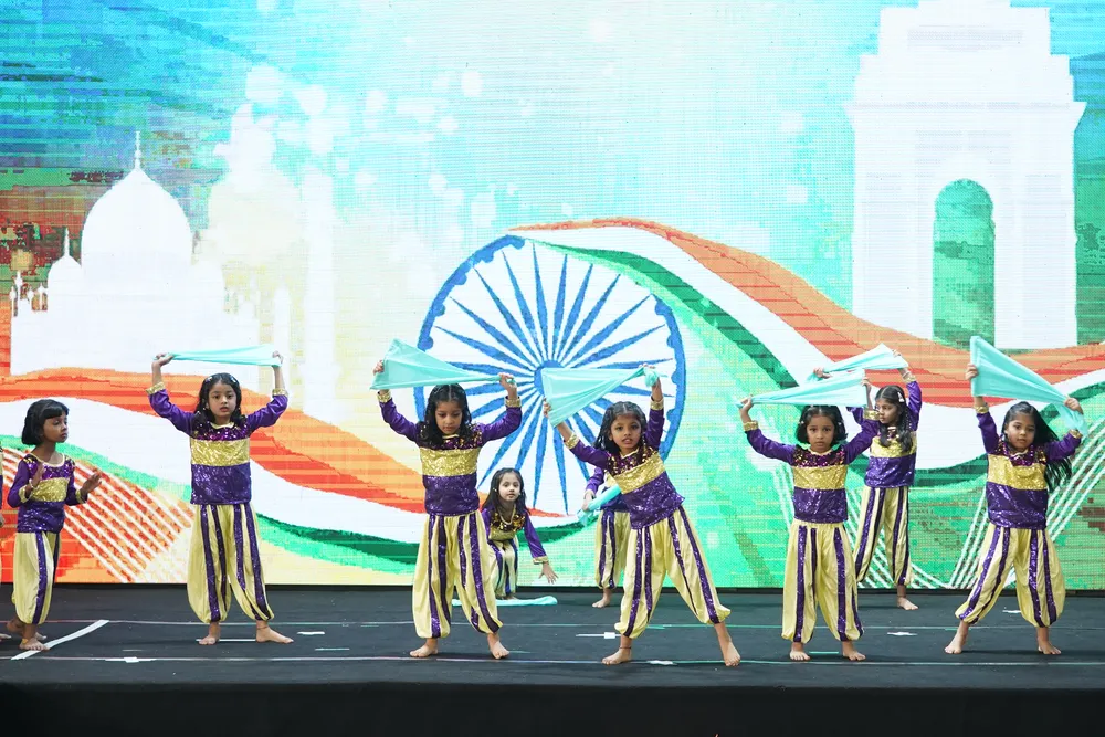 Children performing in front of an India Gate and tricolour backdrop