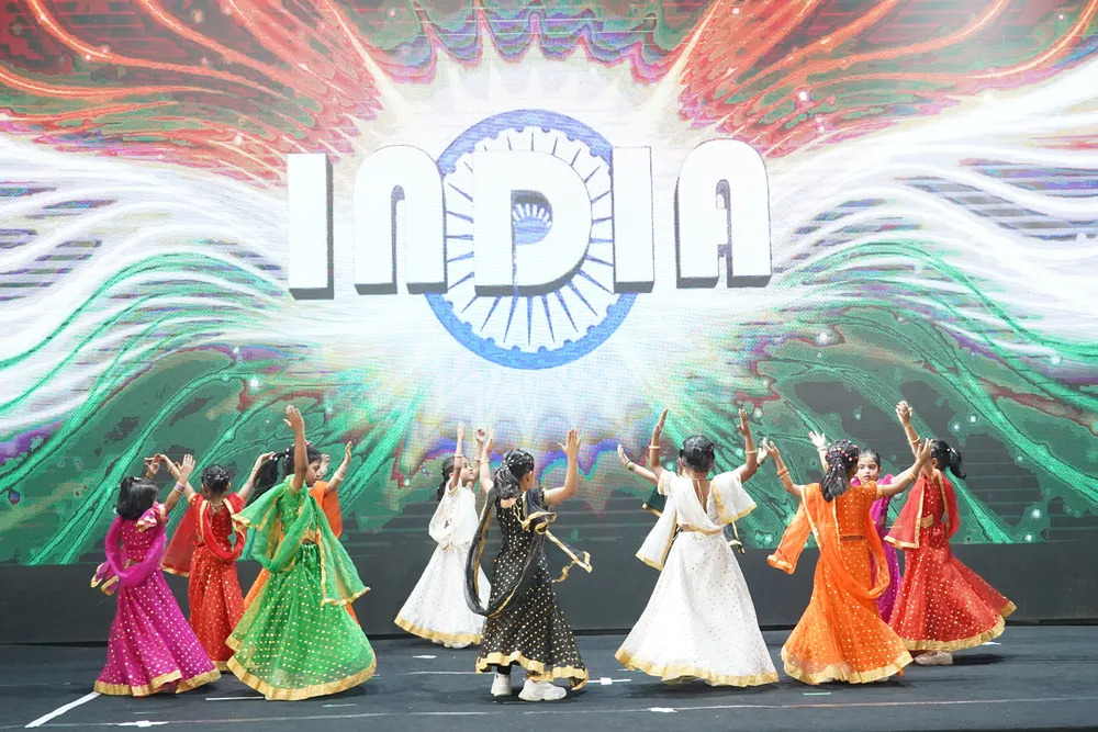 Children in traditional costumes dancing beneath an India backdrop