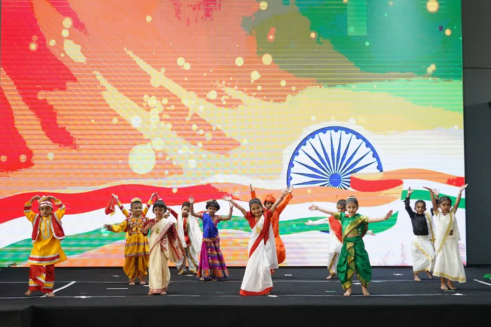 Children dancing in tricolour costumes on stage