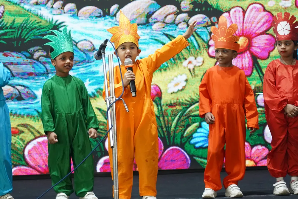 Children in green and orange costumes performing a meadow-themed act