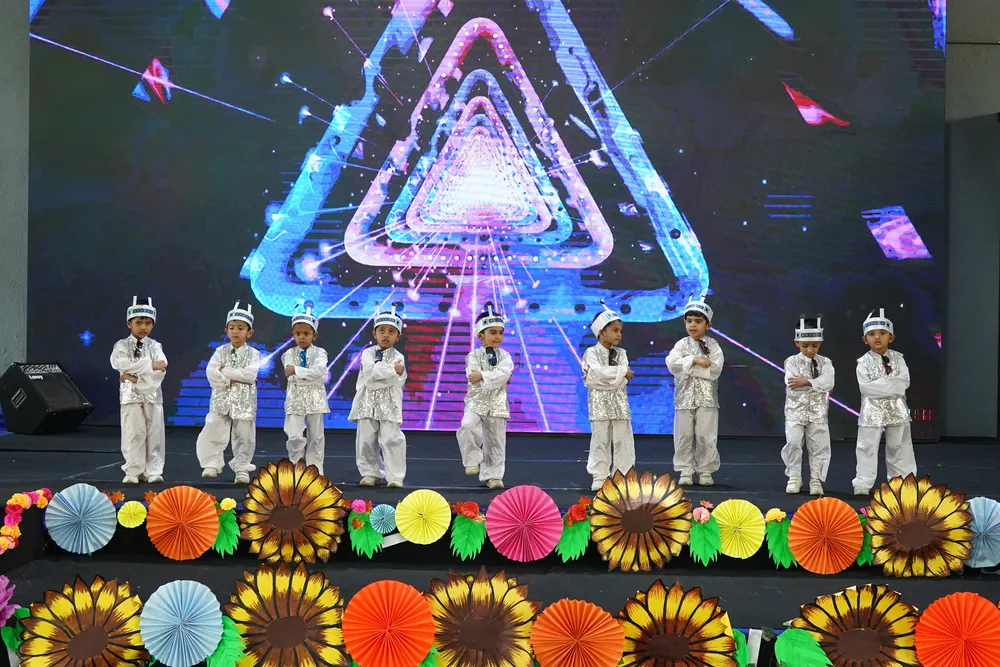 Children in white on stage under a glowing triangle backdrop