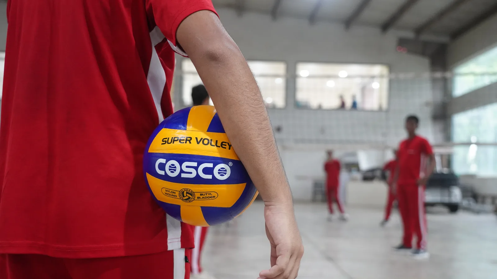 A student about to serve a volleyball